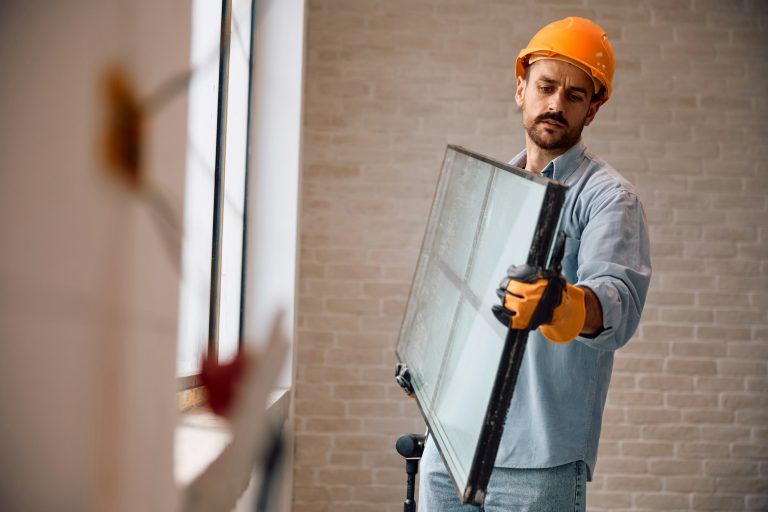 Construction worker changing windows during house renovation.