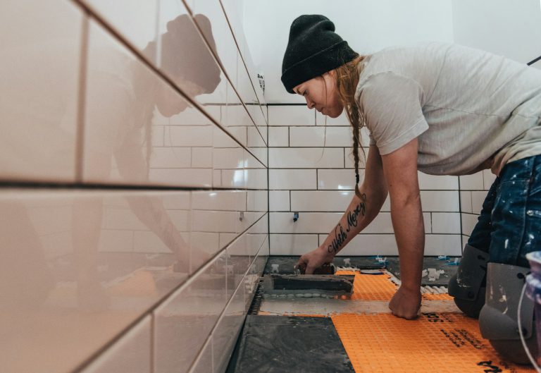 Masonry with white subway tiles and black slate floor tiles and woman worker - DIY bathroom remodel